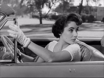 Movie still from “A Place in the Sun” (1951), directed by George Stevens – A woman driving a car in a vintage photo; Close Up shot, Low angle