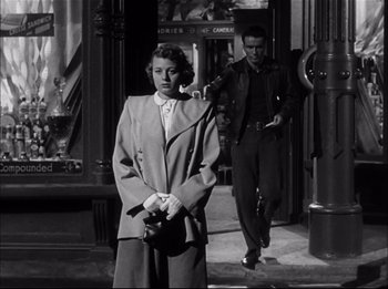 Movie still from “A Place in the Sun” (1951), directed by George Stevens – An old photo of a man and a woman standing on the sidewalk; Medium shot, Low angle