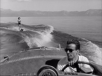 Movie still from “A Place in the Sun” (1951), directed by George Stevens – A man riding a boat on top of a body of water; Wide shot, Low angle