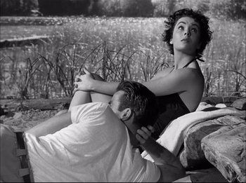 Movie still from “A Place in the Sun” (1951), directed by George Stevens – A man and a woman sitting on the ground; Medium shot, High angle
