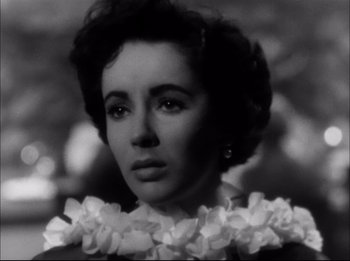Movie still from “A Place in the Sun” (1951), directed by George Stevens – A black and white photo of a woman with flowers around her neck; Close Up shot, Low angle