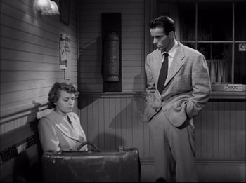 Movie still from “A Place in the Sun” (1951), directed by George Stevens – A man and a woman standing next to each other in front of a suitcase; Medium shot, Low angle