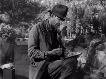 Movie still from “A Place in the Sun” (1951), directed by George Stevens – A black and white photo of a man writing on a paper; Medium shot, Low angle