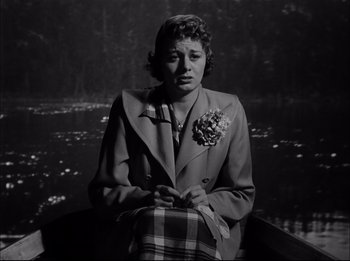 Movie still from “A Place in the Sun” (1951), directed by George Stevens – An old photo of a woman sitting in front of a body of water; Medium shot, High angle