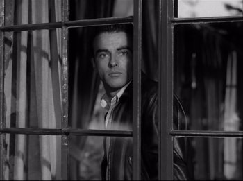 Movie still from “A Place in the Sun” (1951), directed by George Stevens – A black and white photo of a man looking out of a window; Medium shot, High angle
