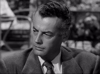Movie still from “A Place in the Sun” (1951), directed by George Stevens – A man in a suit and tie sitting in front of a car; Close Up shot, Low angle