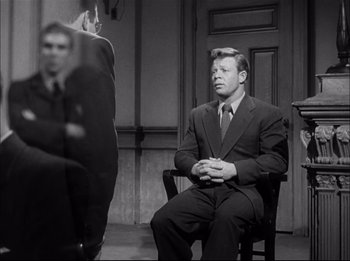 Movie still from “A Place in the Sun” (1951), directed by George Stevens – A man in a suit sitting on a chair; Medium shot, Over the shoulder angle