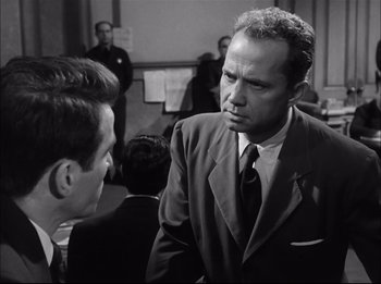 Movie still from “A Place in the Sun” (1951), directed by George Stevens – A man wearing a suit and tie talking to another man in a suit; Medium shot, Over the shoulder angle