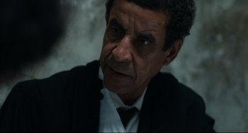 Movie still from “A Prophet” (2009), directed by Jacques Audiard – An older man in a suit and tie looking into the distance; Close Up shot, Over the shoulder angle