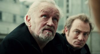 Movie still from “A Prophet” (2009), directed by Jacques Audiard – A man with white hair and blue eyes looking at the camera; Close Up shot, Over the shoulder angle