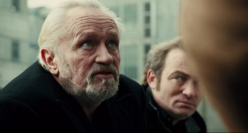 Movie still from “A Prophet” (2009), directed by Jacques Audiard – Two older men with grey hair and blue eyes; Close Up shot, Over the shoulder angle