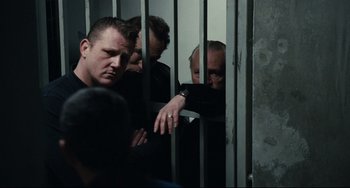 Movie still from “A Prophet” (2009), directed by Jacques Audiard – A group of men standing behind a metal fence; Medium shot, Over the shoulder angle