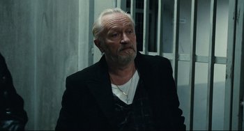 Movie still from “A Prophet” (2009), directed by Jacques Audiard – An older man with a beard and a white beard; Close Up shot, Over the shoulder angle