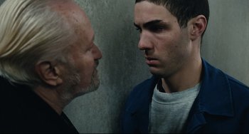 Movie still from “A Prophet” (2009), directed by Jacques Audiard – A man and an older man face each other in front of a concrete wall; Close Up shot, Over the shoulder angle