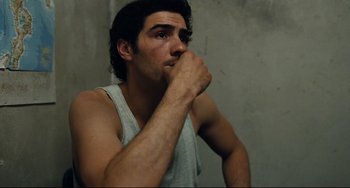 Movie still from “A Prophet” (2009), directed by Jacques Audiard – A young man is sitting in front of a concrete wall; Close Up shot, High angle