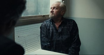 Movie still from “A Prophet” (2009), directed by Jacques Audiard – An older man sitting in front of a window; Medium shot, Over the shoulder angle