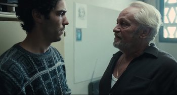 Movie still from “A Prophet” (2009), directed by Jacques Audiard – A man and a boy talking to each other; Medium shot, Over the shoulder angle