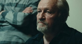 Movie still from “A Prophet” (2009), directed by Jacques Audiard – An older man with a beard and mustache; Close Up shot, Low angle