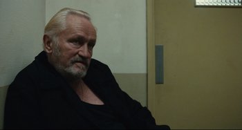 Movie still from “A Prophet” (2009), directed by Jacques Audiard – An older man sitting in front of a door; Close Up shot, Over the shoulder angle