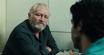 Movie still from “A Prophet” (2009), directed by Jacques Audiard – An older man sitting in front of another man in a room; Close Up shot, Over the shoulder angle