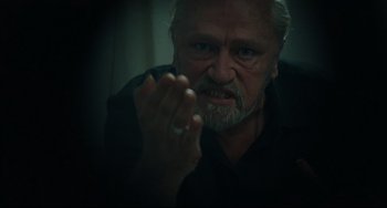 Movie still from “A Prophet” (2009), directed by Jacques Audiard – An older man with gray hair and a goatee is looking at the camera; Close Up shot, Over the shoulder angle