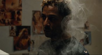 Movie still from “A Prophet” (2009), directed by Jacques Audiard – A man with curly hair is smoking in a room; Close Up shot, Low angle