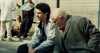 Movie still from “A Prophet” (2009), directed by Jacques Audiard – Two men sitting next to each other on the ground; Medium shot, Over the shoulder angle