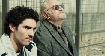 Movie still from “A Prophet” (2009), directed by Jacques Audiard – Two men sitting next to each other wearing sunglasses; Medium shot, Low angle