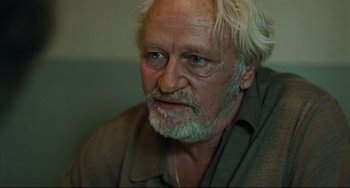 Movie still from “A Prophet” (2009), directed by Jacques Audiard – An older man with white hair and a gray beard; Close Up shot, Over the shoulder angle