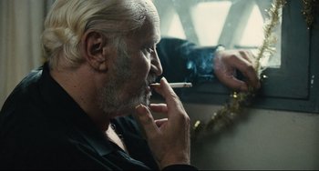 Movie still from “A Prophet” (2009), directed by Jacques Audiard – An older man smoking a cigarette while sitting in a car; Close Up shot, Over the shoulder angle