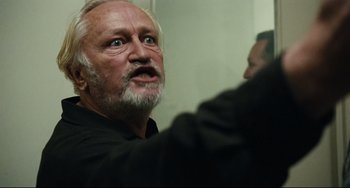 Movie still from “A Prophet” (2009), directed by Jacques Audiard – An older man with a beard and mustache looking into a mirror; Close Up shot, Low angle