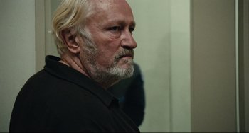 Movie still from “A Prophet” (2009), directed by Jacques Audiard – An older man with white hair and a goatee looking into a mirror; Close Up shot, Over the shoulder angle