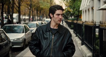 Movie still from “A Prophet” (2009), directed by Jacques Audiard – A man in a leather jacket standing on a sidewalk; Close Up shot, Over the shoulder angle