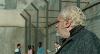 Movie still from “A Prophet” (2009), directed by Jacques Audiard – An older man with white hair looking off into the distance; Close Up shot, Over the shoulder angle