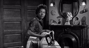 A black and white photo of a woman ironing clothes