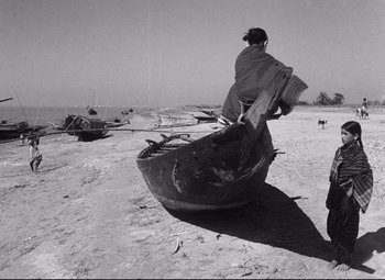 A woman sitting on top of a boat on a beach