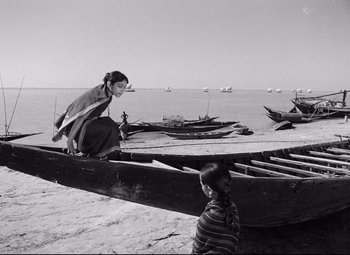 A woman sitting on the end of a boat on the beach