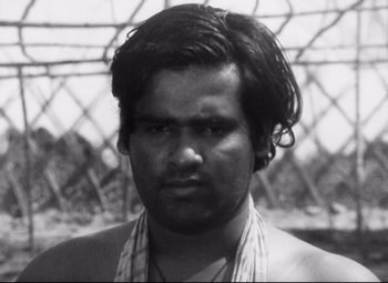 Movie still from “A River Called Titas” (1973), directed by Ritwik Ghatak – Black and white photograph of a man with long hair; Close Up shot, Low angle