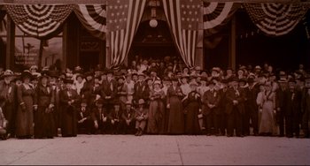 Movie still from “A River Runs Through It” (1992), directed by Robert Redford – A group of people standing in front of an american flag; Extreme Wide shot, High angle