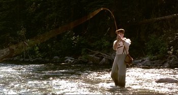 Movie still from “A River Runs Through It” (1992), directed by Robert Redford – A man standing in a river holding a fishing rod; Wide shot, Low angle