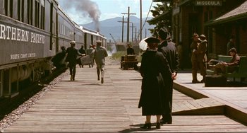 Movie still from “A River Runs Through It” (1992), directed by Robert Redford – A group of people standing next to a train; Extreme Wide shot, High angle