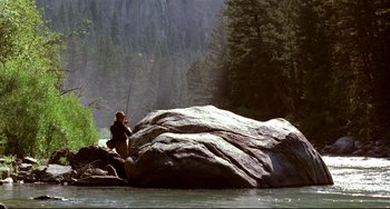 Movie still from “A River Runs Through It” (1992), directed by Robert Redford – A man standing on a rock near a river; Extreme Wide shot, High angle