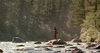 Movie still from “A River Runs Through It” (1992), directed by Robert Redford – A man standing on top of a rock in the middle of a river; Wide shot, Low angle