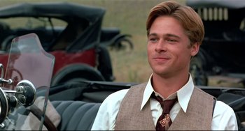 Movie still from “A River Runs Through It” (1992), directed by Robert Redford – A man wearing a suit and tie in front of an antique car; Close Up shot, Over the shoulder angle