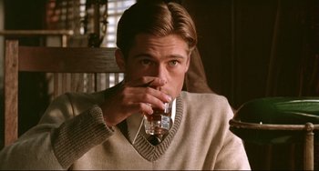 Movie still from “A River Runs Through It” (1992), directed by Robert Redford – A man in a sweater drinking a glass of water; Medium shot, Over the shoulder angle