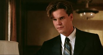 Movie still from “A River Runs Through It” (1992), directed by Robert Redford – A man in a black suit and a blue striped tie; Close Up shot, Low angle