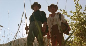 Movie still from “A River Runs Through It” (1992), directed by Robert Redford – Two men standing in tall grass holding fishing rods; Medium shot, Low angle