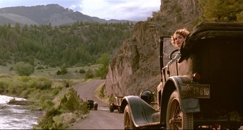 Movie still from “A River Runs Through It” (1992), directed by Robert Redford – A woman driving an antique car down a road; Wide shot, Low angle