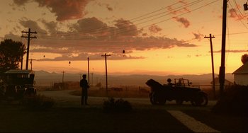 Movie still from “A River Runs Through It” (1992), directed by Robert Redford – A man standing on the side of a road next to a truck; Extreme Wide shot, Low angle