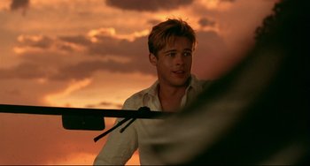 Movie still from “A River Runs Through It” (1992), directed by Robert Redford – A man in a white shirt is standing in front of a sunset; Close Up shot, Over the shoulder angle